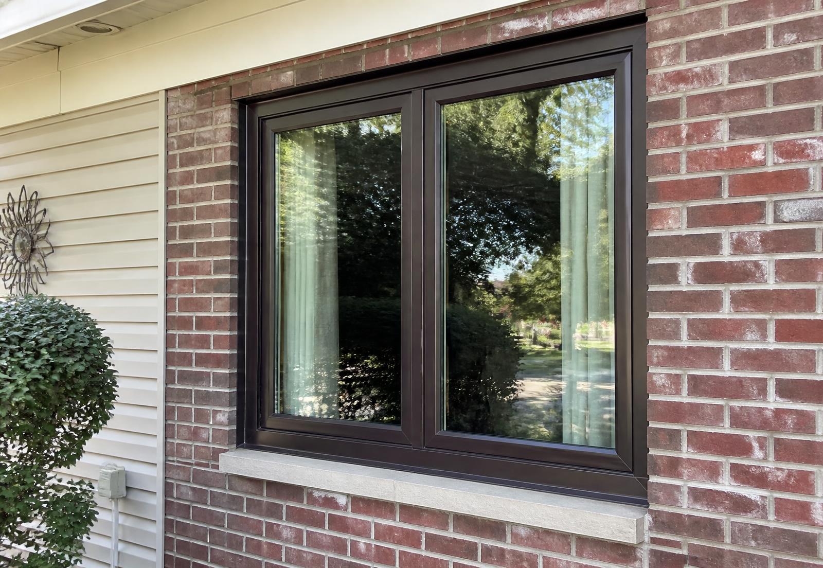 Dark bronze aluminum casement window installed in a brick and siding home exterior